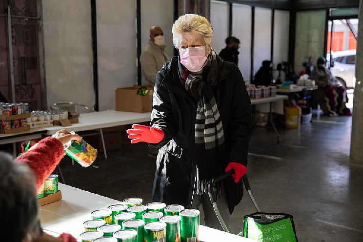 Mary Hostetter picks up food at a pop-up food bank organized by White Center Food Bank at Arrowhead Gardens Senior Apartments on Thursday. Food banks are expecting a surge after Congress recently voted to cut SNAP benefits back to pre-pandemic levels. (Amanda Snyder/Crosscut)