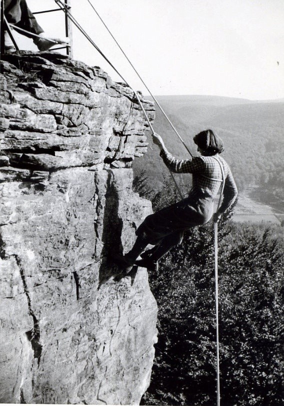 Helga Byhre rappelling with the help of a rope. She escaped Germany during Hitler's time in this way. Note that she's wearing a skirt for her mountain climbing.