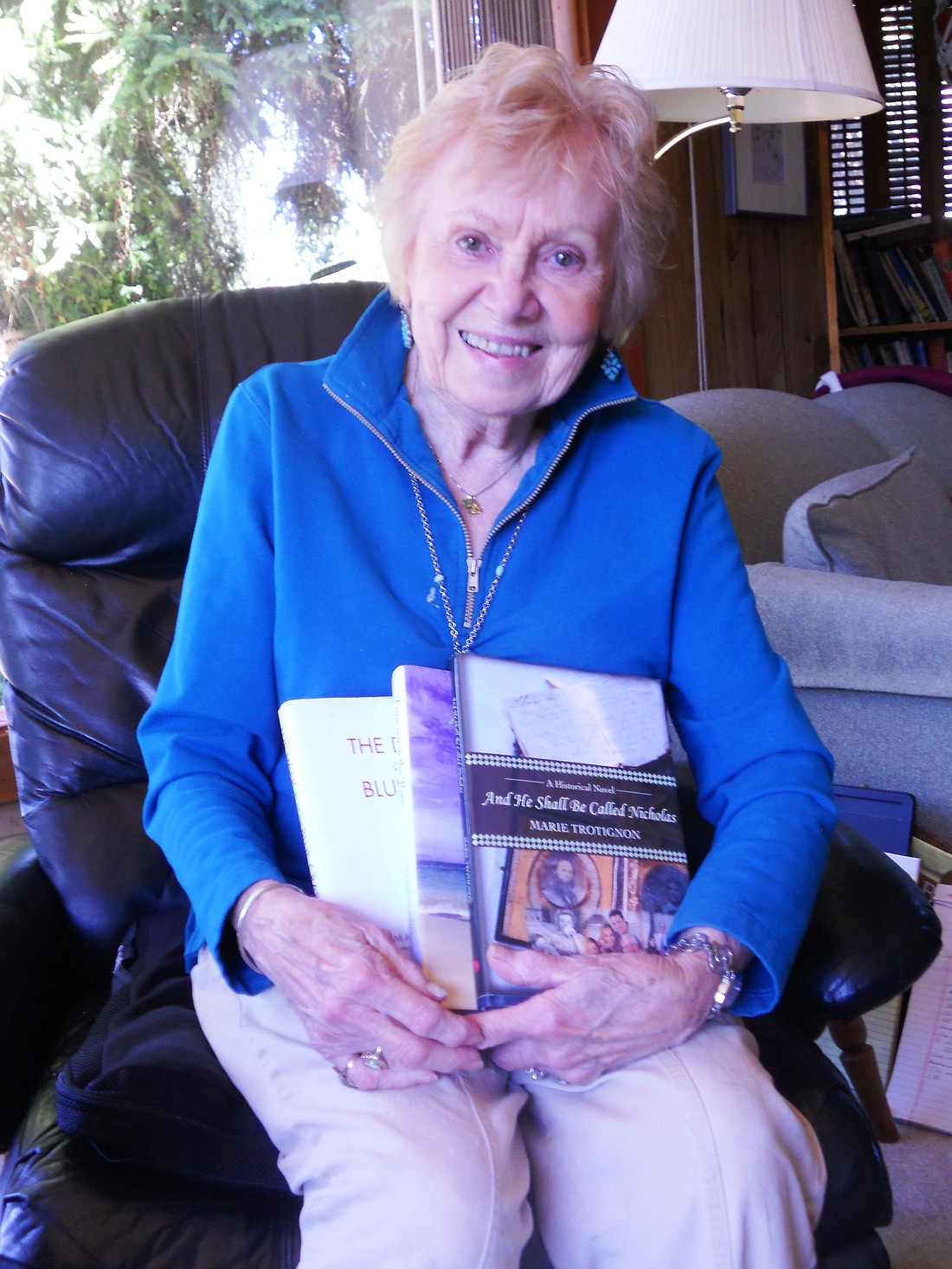 Marie displays her three published books: "Dancing in the Rain: A Collection of Raindrops and Rainbows," "And He Shall Be Called Nicholas," and "The Dance of the Blue Crab."
