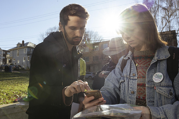 Ben Ferlo (left), a field organizer for the Prop 1A campaign, shows a volunteer where the group will be knocking on doors on Capitol Hill to gather support for the ballot proposition, which would tax large businesses to fund social housing in Seattle, on Jan. 19, 2025. (Charissa Soriano for Cascade PBS)